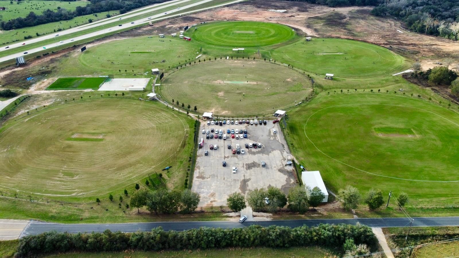 Aerial view over Prairie View Cricket Complex showing several full-size natural turf grounds and the car park.